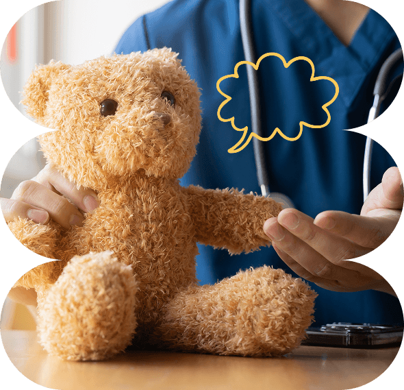 A person in blue scrubs and a stethoscope gestures to a brown teddy bear. A yellow speech bubble is drawn near the bear’s head, suggesting the bear is speaking or being spoken to during a pretend check-up—perfect for illustrating the compassionate care provided by Galways Sick Kids.