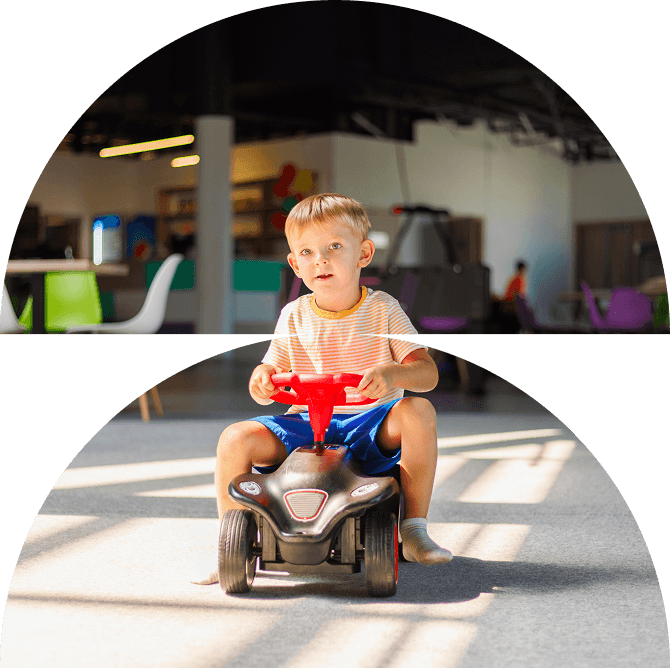 A young boy in a striped shirt rides a small black toy car indoors at Galways Sick Kids. Bright sunlight shines on the floor, and colourful chairs and tables are visible in the background.